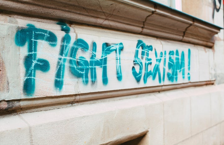 white background wall with graffiti with fight sexism written
