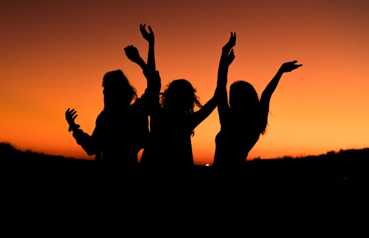 silhouette of three women with hands up