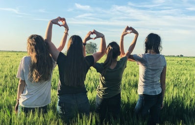 four girls standing united in a grass meadow