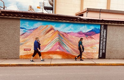 Two people walking by a wall