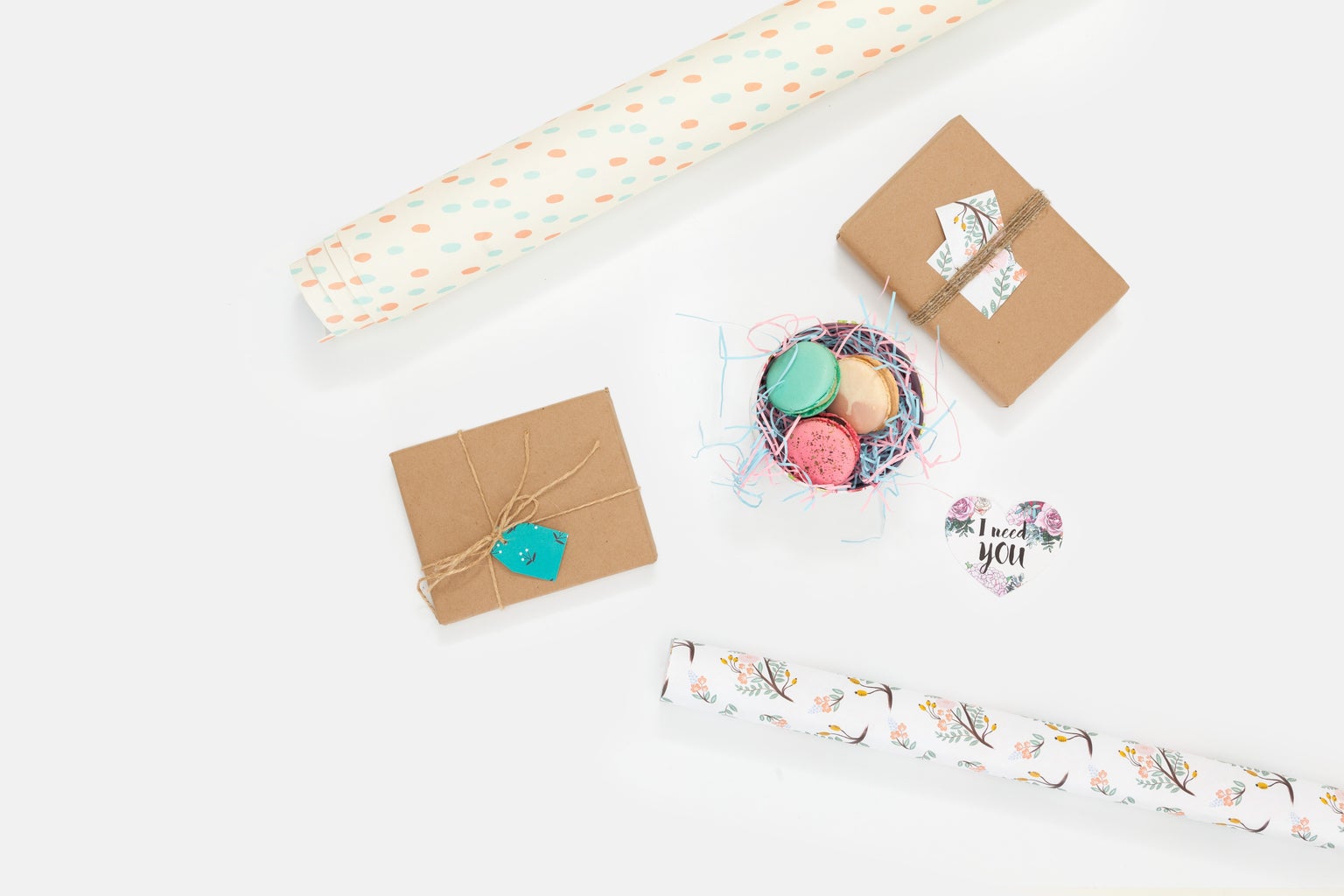 flat lay photography of wallpaper and brown paper packages with bowl of macarons