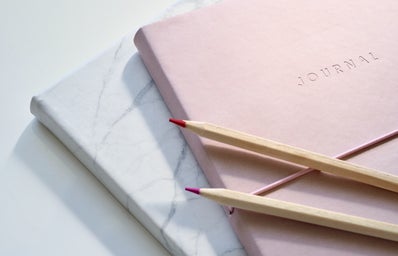 red and purple coloring pencils on pink and white marble journals