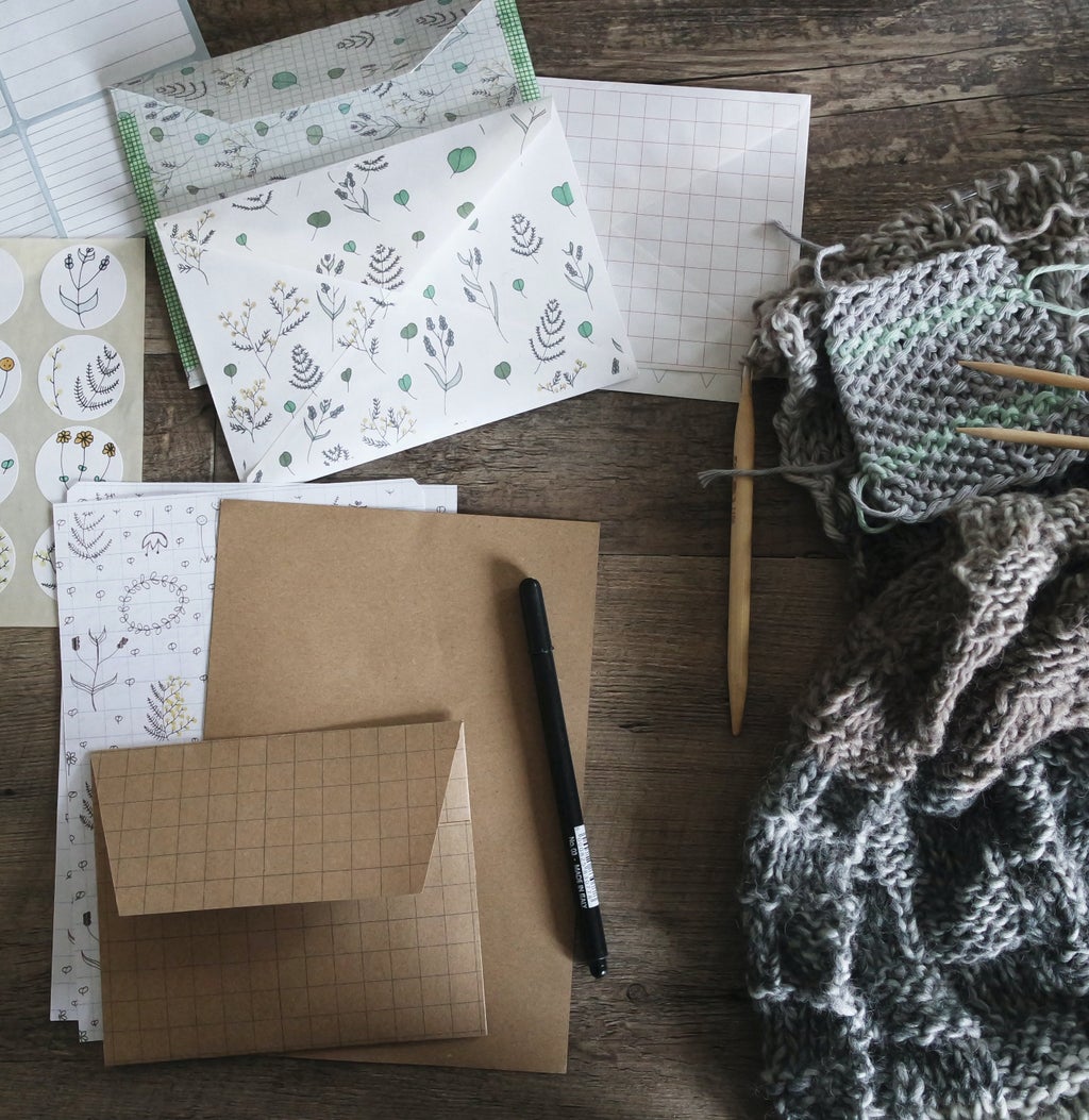 black pen beside envelopes and stationary with leaf doodles and knit scarf