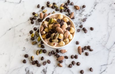 a cup of almonds, assorted nuts, and chocolate chips