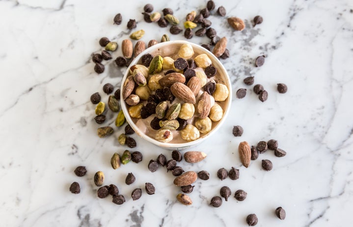a cup of almonds, assorted nuts, and chocolate chips