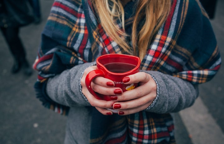 Red nails, woman holding tea, plaid scarf