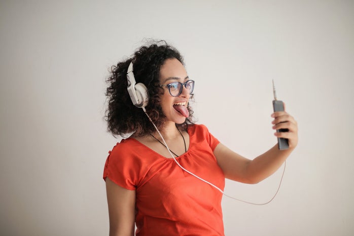 person wearing headphones taking selfie on smartphone
