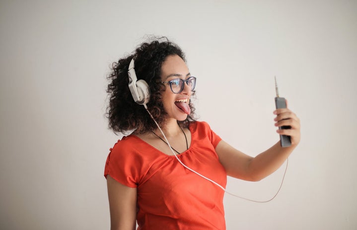 person wearing headphones taking selfie on smartphone