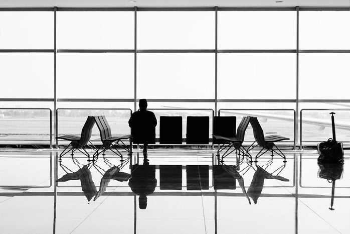 silhouette of person sitting alone in airport waiting area