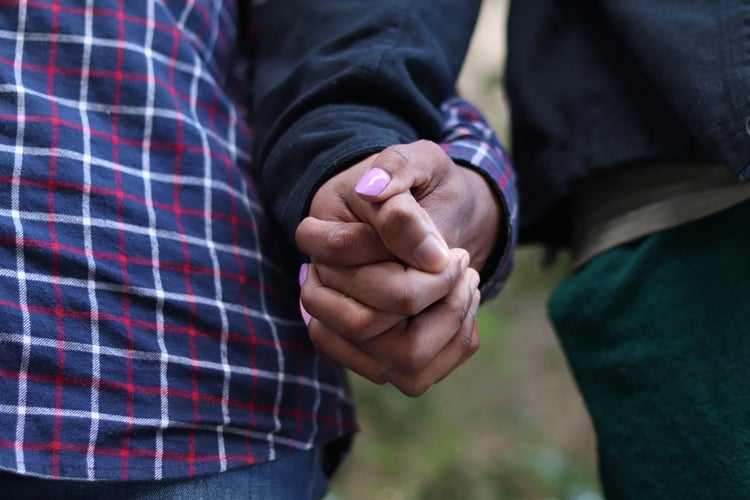 Two men hold hands.