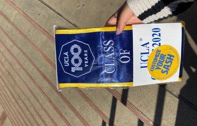 hand holding a ucla class of 2020 sash inside packaging