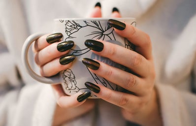 woman with black monochrome manicure holding a black and white patterned mug