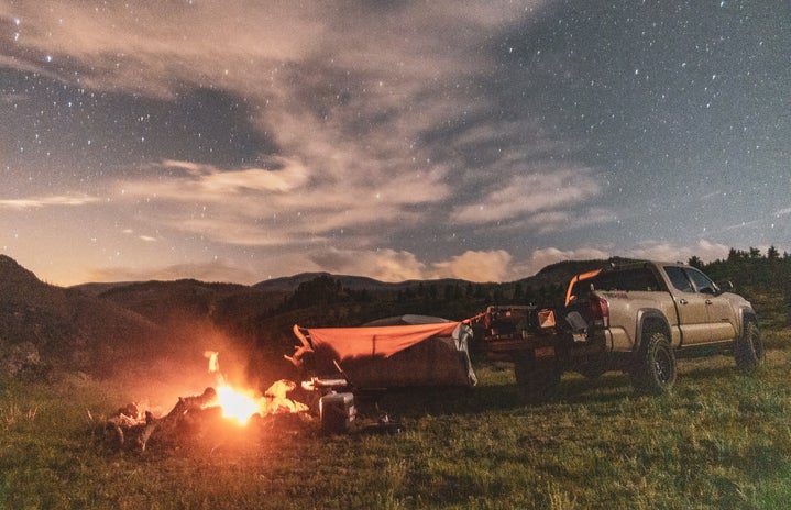 Stars behind pickup truck and bonfire