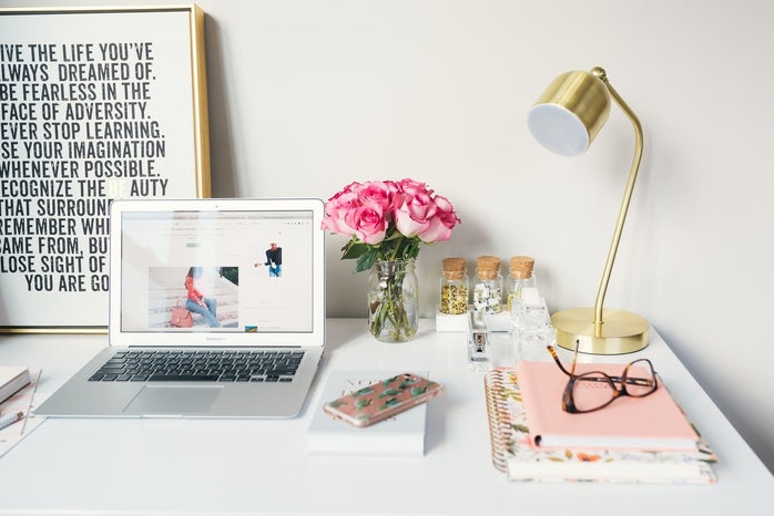 laptop open on white desk with pink and golden accents