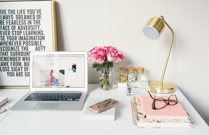 laptop open on white desk with pink and golden accents