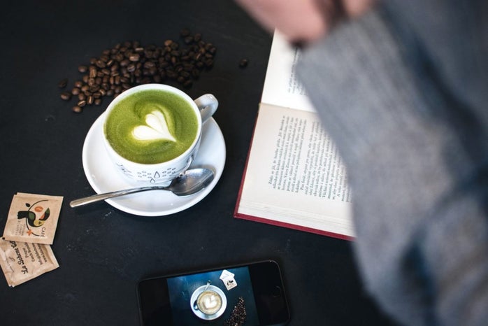 dark cafe desk with phone, matcha latte, and book.