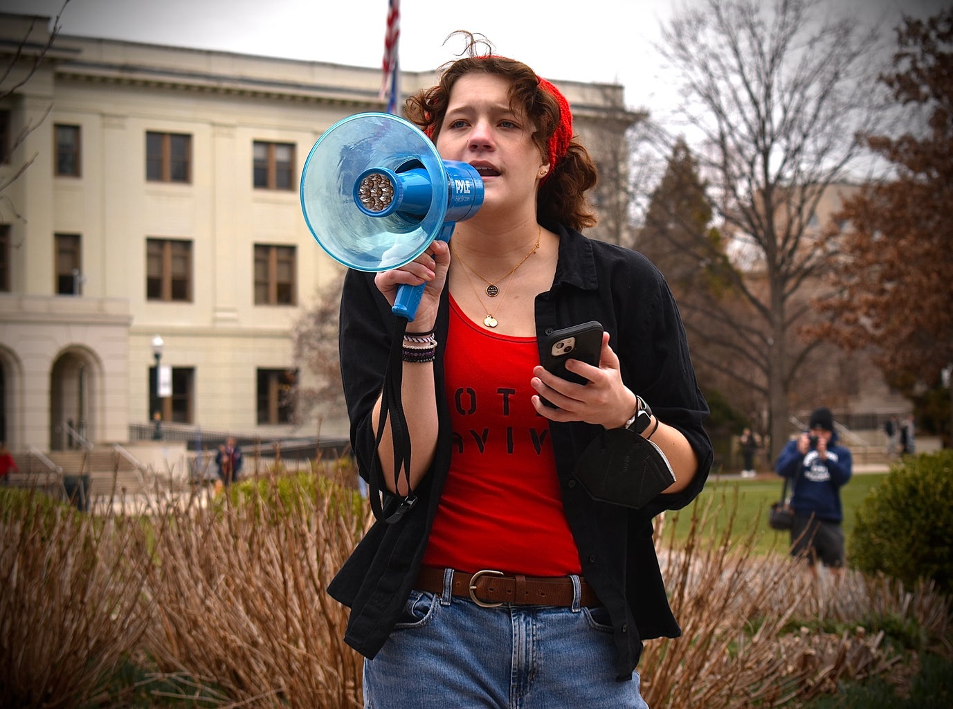 College-aged woman speaking with a bullhorn at a protest.