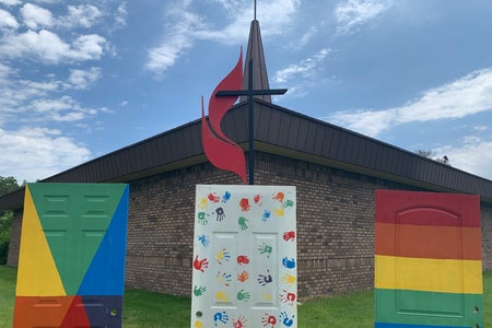 Rainbow painted doors in front of metal cross