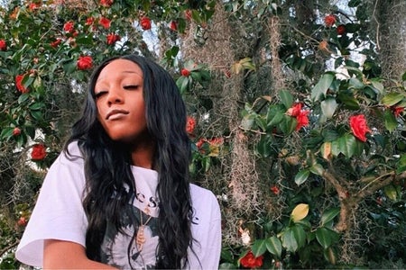 Girl in a white shirt in front of an ivy and roses-covered wall