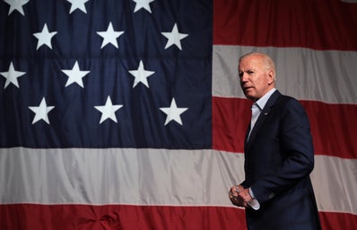 Joe Biden speaking in front of an American flag