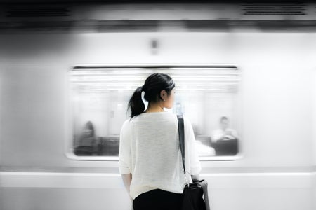 woman standing in front of moving subway train
