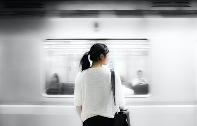 woman standing in front of moving subway train