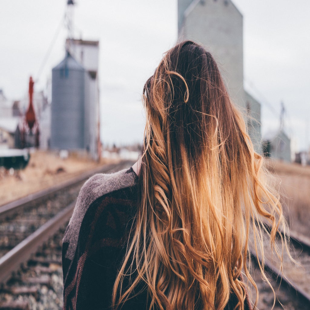 shallow focus photography of woman standing on train rail