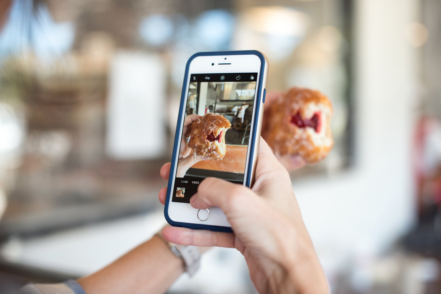 selective focus photography of person taking picture of jelly donut