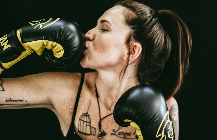 woman kissing black leather boxing gloves