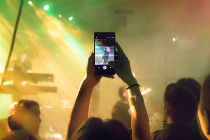 person taking a a photo with phone at a concert