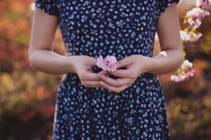 woman in blue dress holding a pink flower