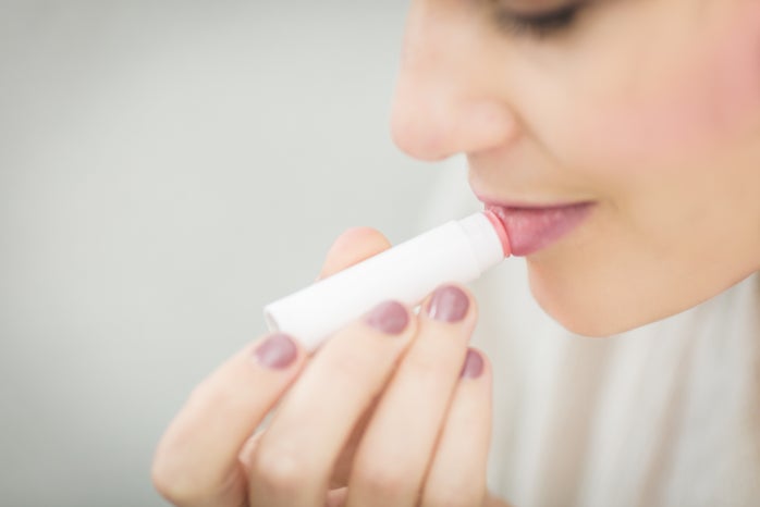 woman putting lip balm on