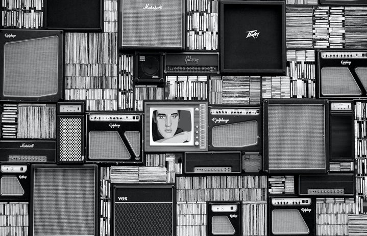 black and white wall of records, speakers, and a TV in the center with the image of Elvis Presley
