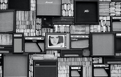 black and white wall of records, speakers, and a TV in the center with the image of Elvis Presley