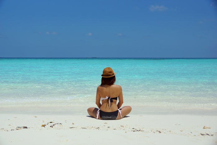 Woman Wearing Black and White Brassiere Sitting on White Sand