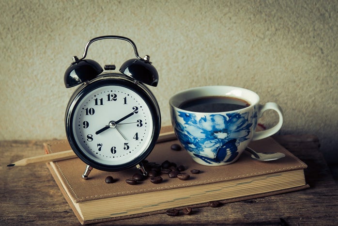 coffee in a blue pattern mug next to an analog alarm clock