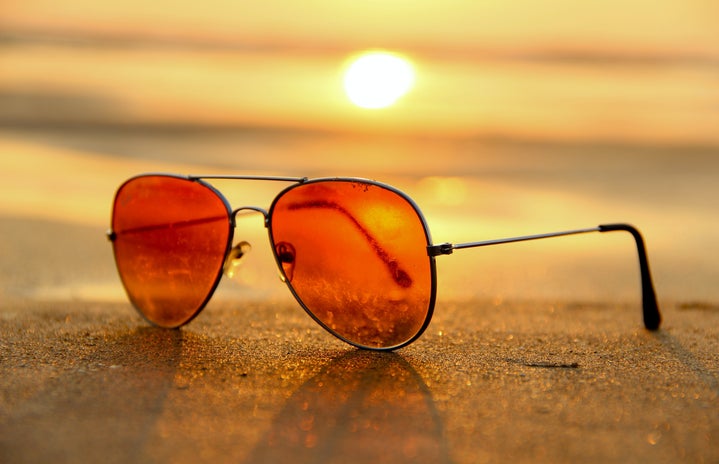 close-up of orange aviator sunglasses on sand at beach