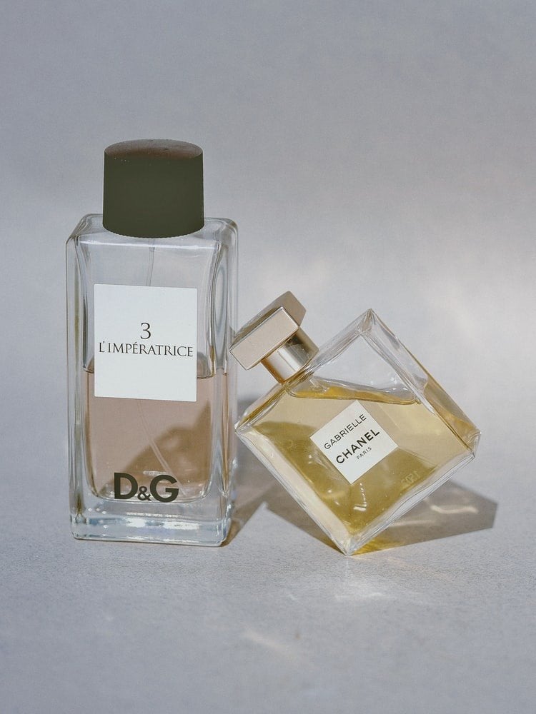 product shot of two designer perfumes, one leaning against the other