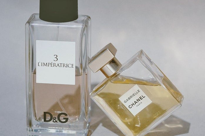 product shot of two designer perfumes, one leaning against the other