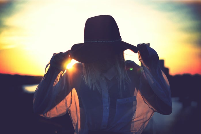 silhouette of woman holding her hat