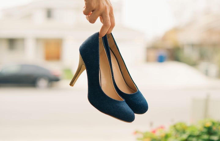 low-depth of field photo of person holding navy stilletos