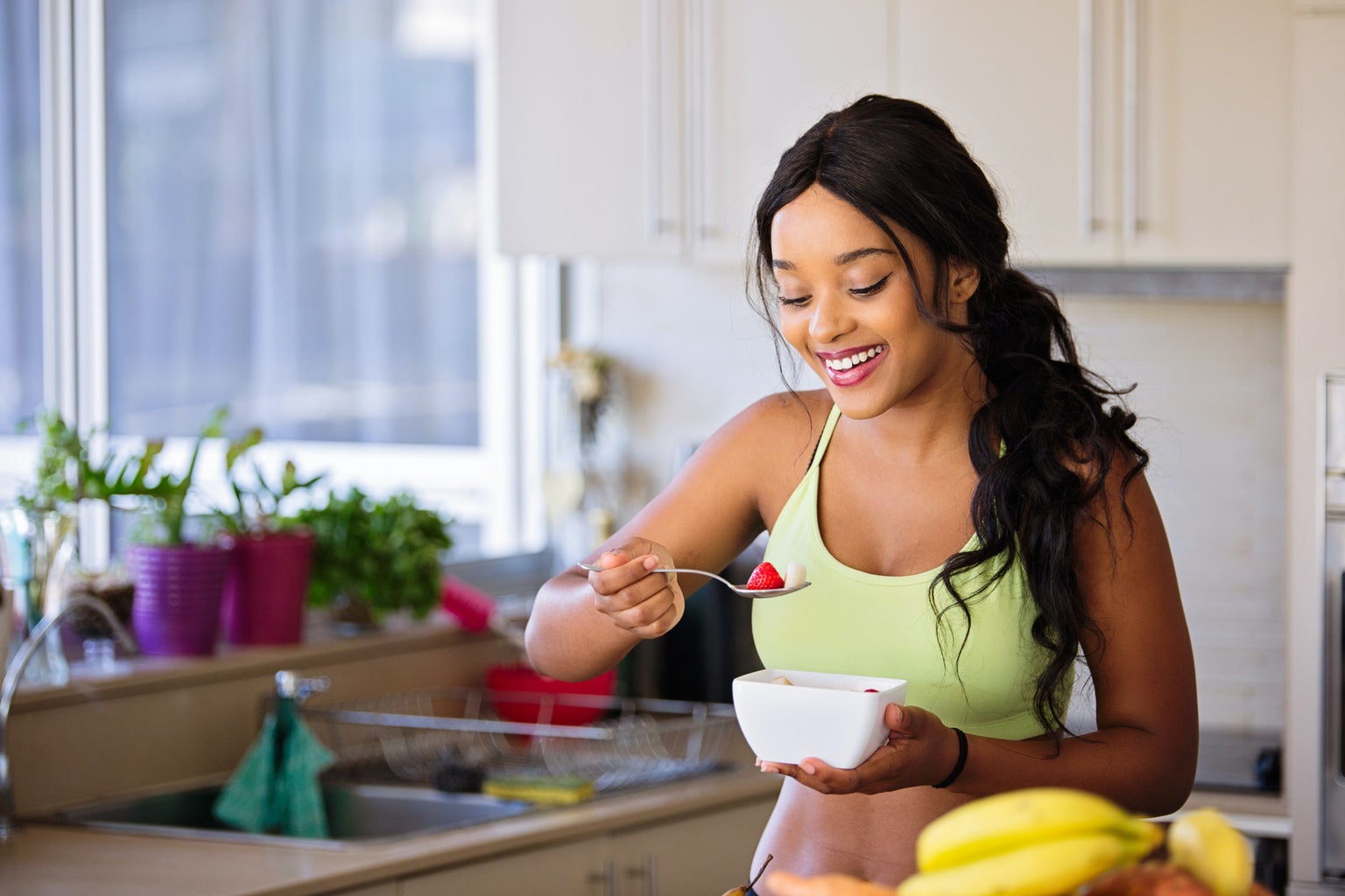 woman eating fresh fruit in a sports bra