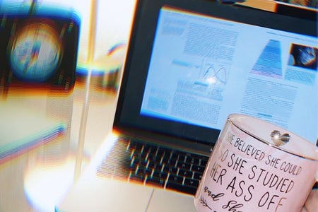 Student holding coffee cup while studying at desk