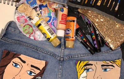 Painted jeans with paint bottles and brushes around them