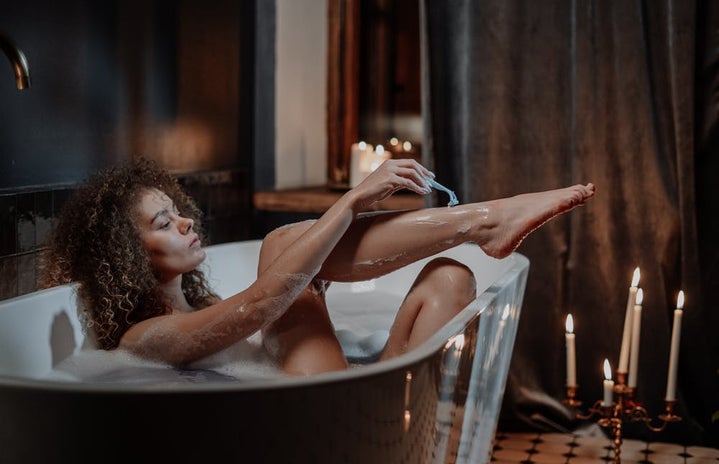 Woman shaving her legs in the bathtub