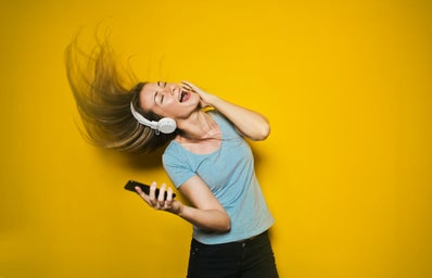 Woman wearing white headphones and dancing