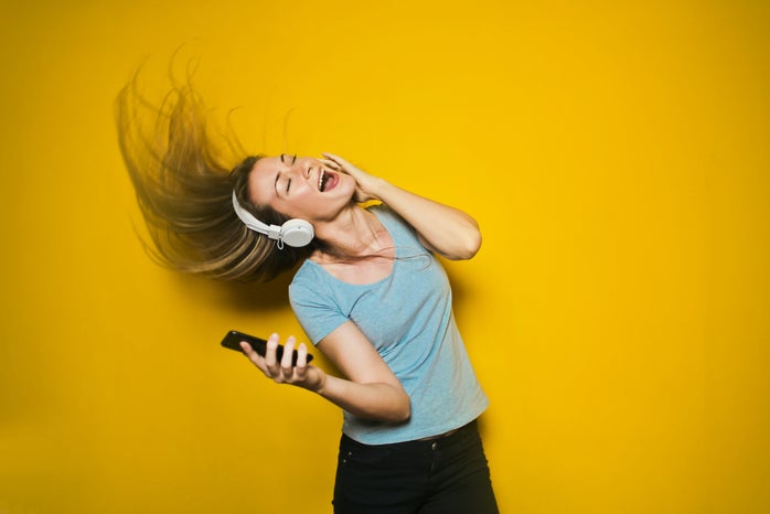 Woman wearing white headphones and dancing