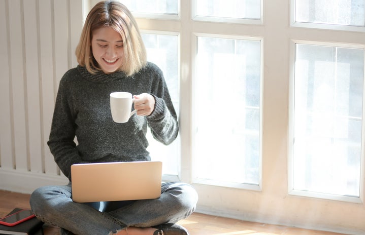 Woman sitting at computer drinking coffee