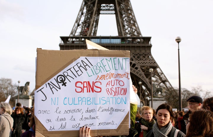 protestors in front of Eiffel tower, sign in foreground displaying pro-choice message