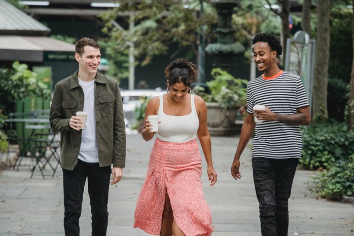 young friends walking in park and smiling with coffee to go